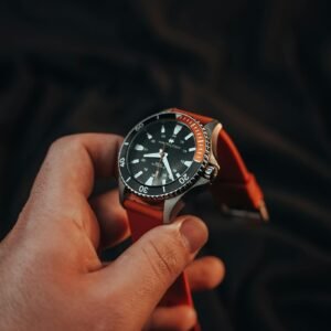 A luxury scuba diving watch with a red strap captured in a close-up shot, symbolizing wealth and style.