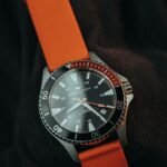 Close-up of a luxury wristwatch with orange strap and black dial, highlighting its elegance and style.