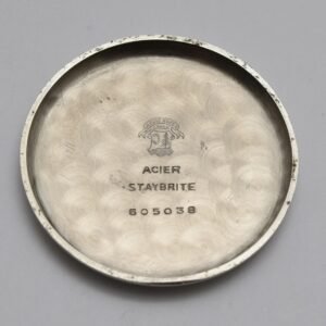 Vintage watch back cover with engravings and logo on a grey background.